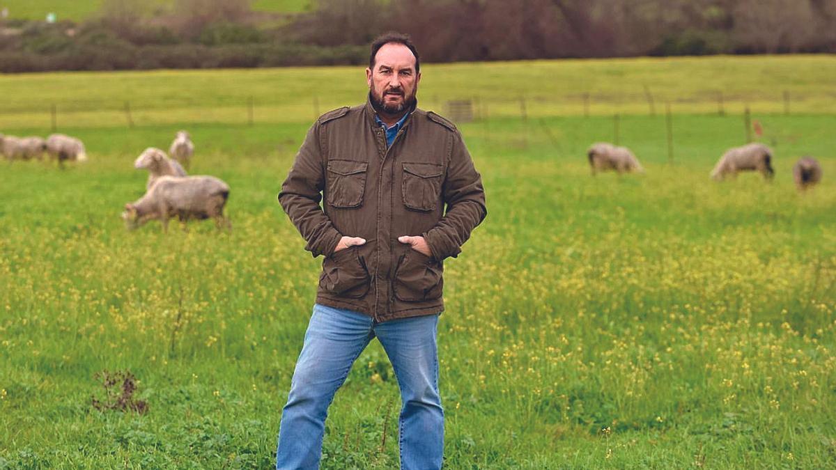 Felipe Molina, sexta generación ganadera de su familia, posa al aire libre con animales de La Albaidas, al fondo.