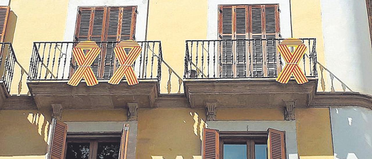 Tres lazos con la bandera cuatribarrada en el balcón de Més en Cort.