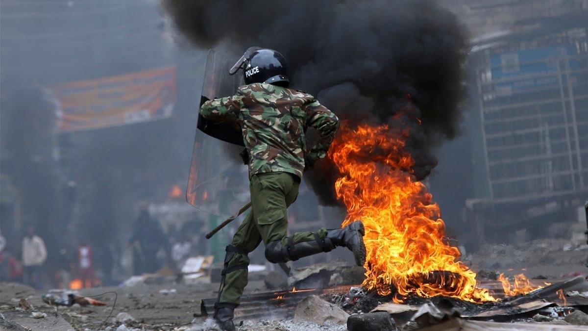 Un agente antidisturbios salta una barricada en llamas levantada por seguidores del opositor Raila Odinga, en Mathare (Nairobi), el 12 de agosto.