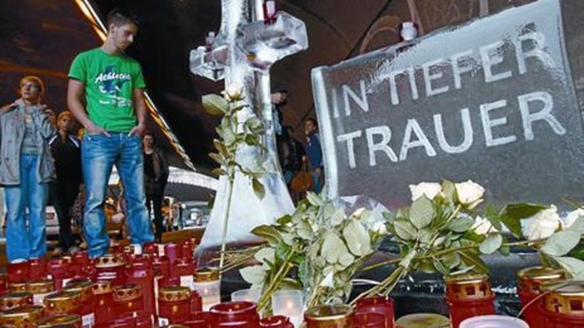 Un joven observa las velas y un cartel que dice «Desde la más profunda tristeza» en el lugar de la tragedia.