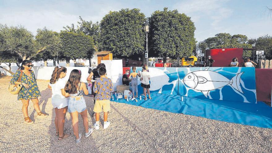 Los pequeños pintan un mural de peces dibujado para ellos. | VICENT MARÍ