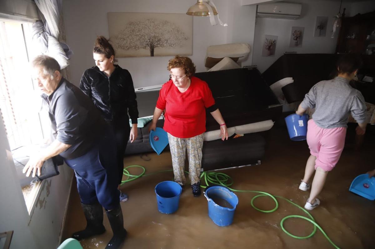 Vecinos de una vivienda de Majaneque limpian y achican agua.