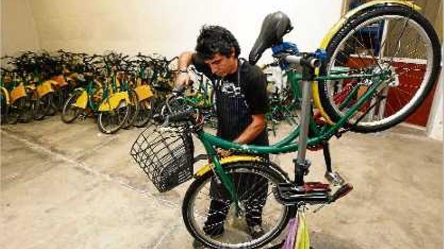 El mecànic treballant al taller del Pont Major amb una de les bicicletes que s&#039;han de reparar.