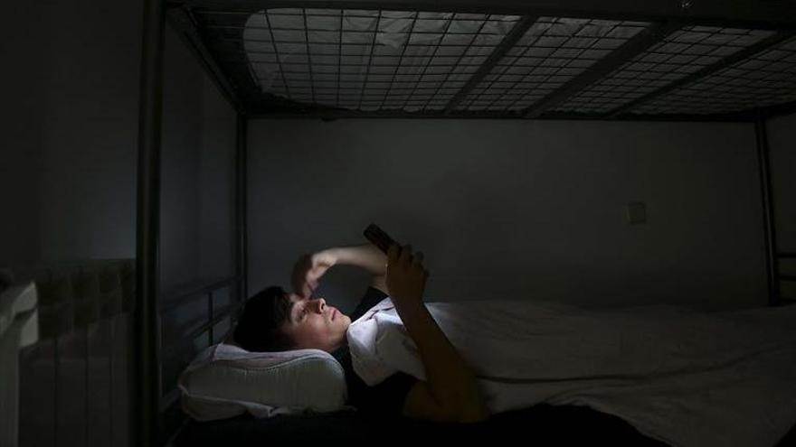 Un adolescente consulta su móvil mientras está acostado.