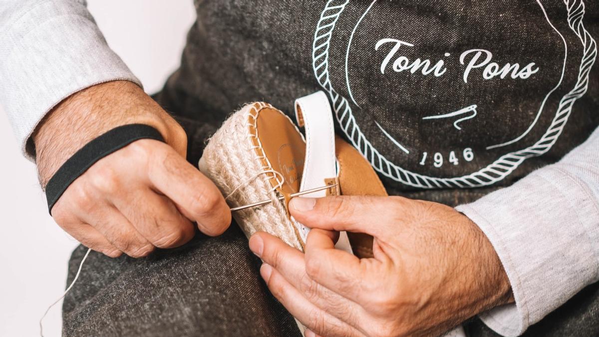 Un artesano, cosiendo a mano una espardeña de Toni Pons.