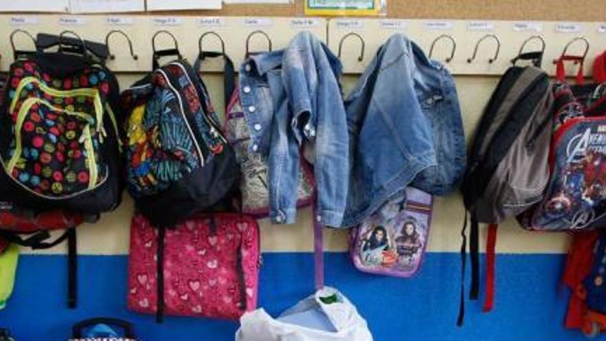 Mochilas y cazadoras colgadas en un perchero, en el primer día de clase.