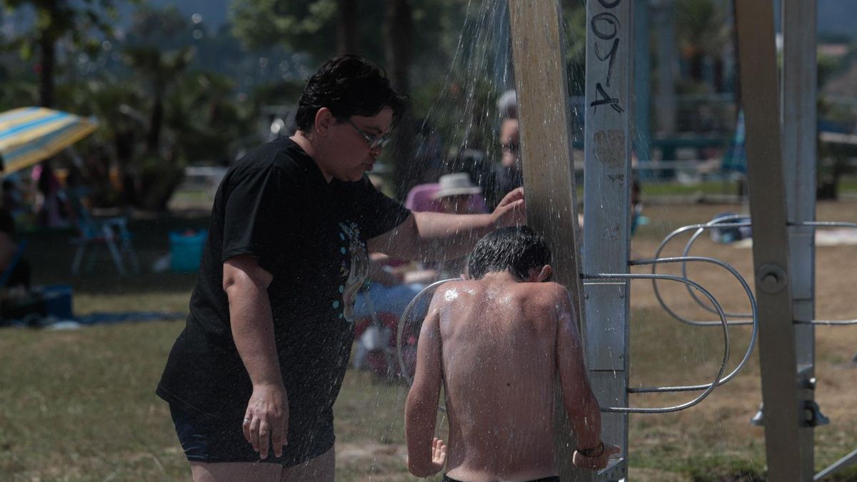 Un niño se refresca en una ducha.