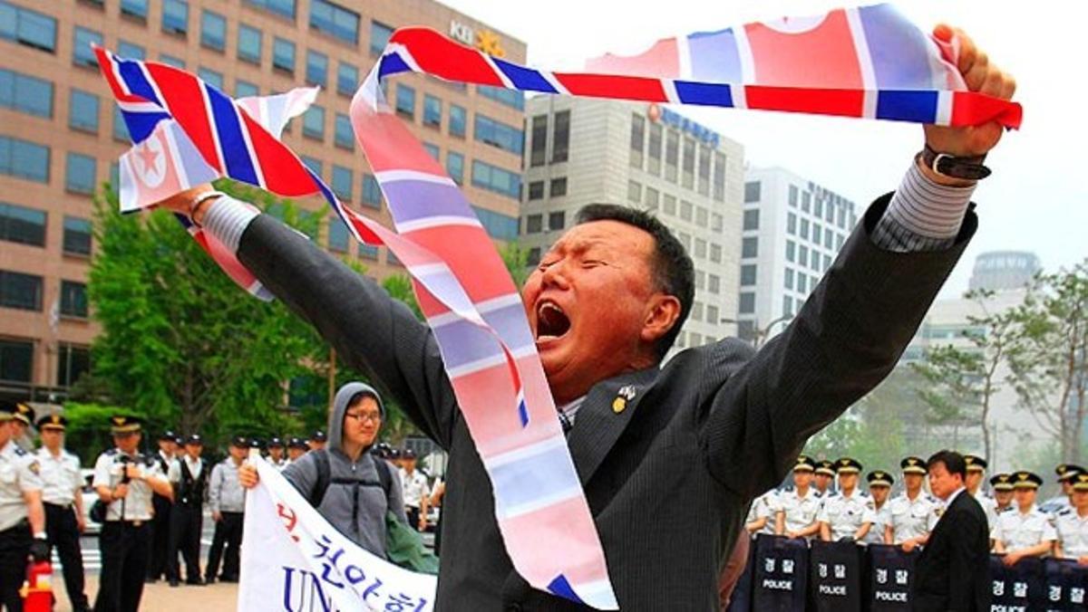 Un manifestant de Corea del Sud trenca una bandera nord-coreana en protesta per l’enfonsament d’un vaixell de guerra del seu país a prop de la frontera entre les dues nacions.