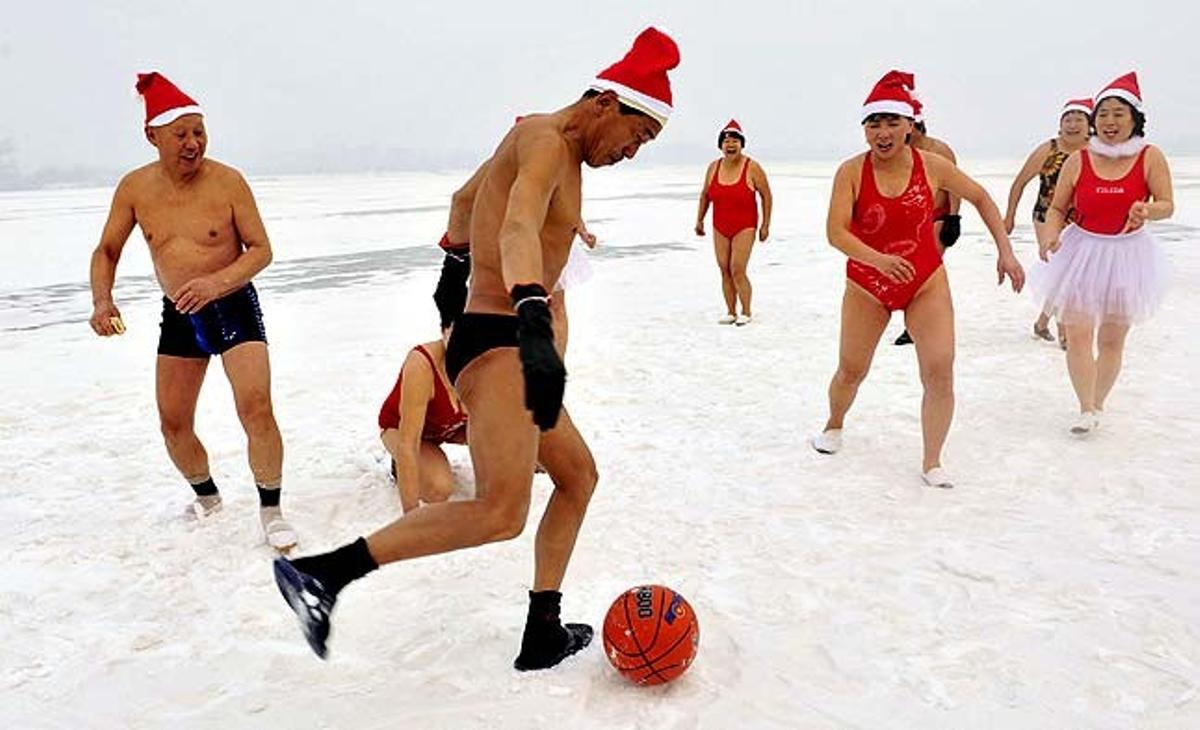Un grup de nedadors, que portaven barrets de Pare Noel, juga amb una pilota en un riu cobert de neu a Shenyang (Xina).