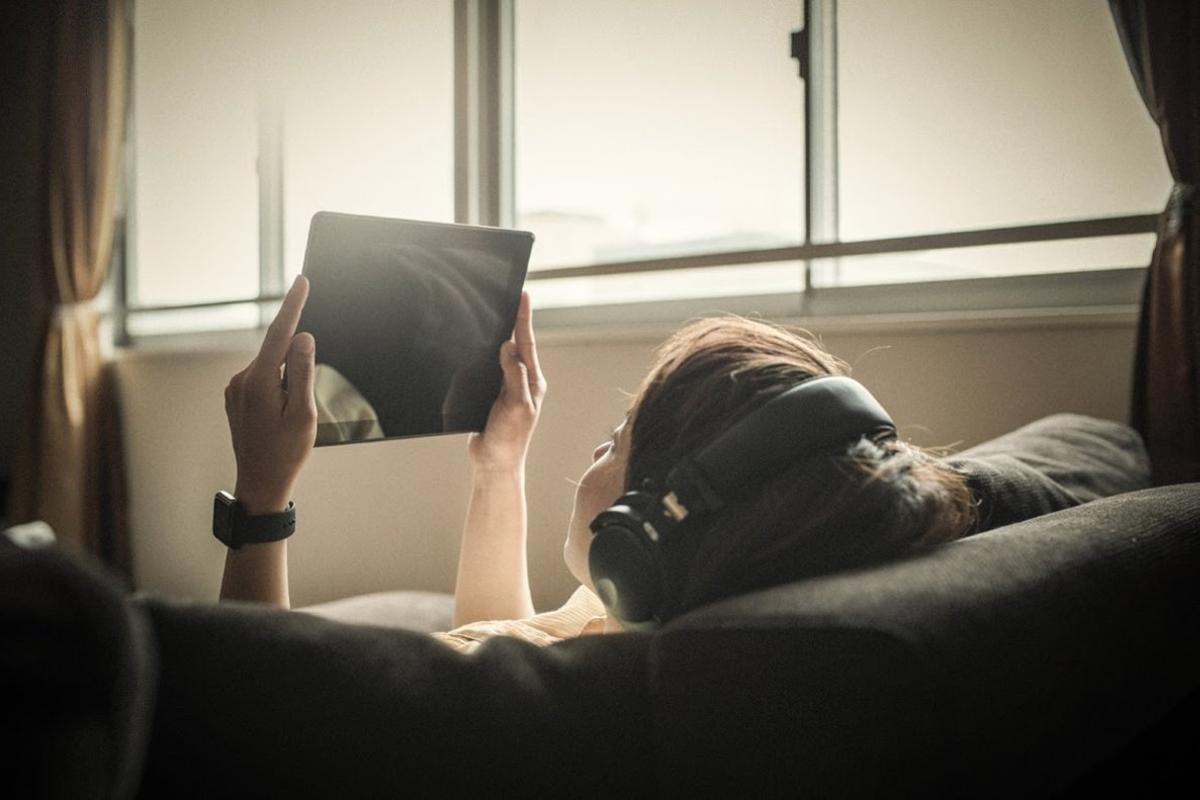 Young adult woman relaxing on a sofa using a digital tablet. Kyoto, Japan. May 2016