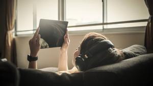 Young adult woman relaxing on a sofa using a digital tablet. Kyoto, Japan. May 2016