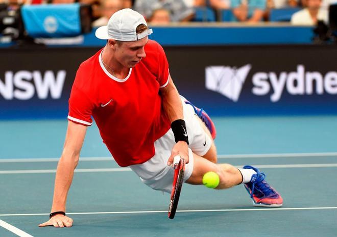 Denis Shapovalov cae y golpea la bola durante su partido individual contra Novak Djokovic durante el torneo de la ATP Cup en Sydney.