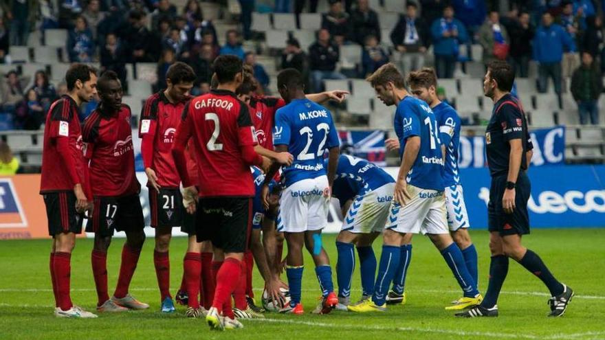 El árbitro, Figueroa Vázquez, observa a jugadores del Oviedo y el Mirandés antes de lanzarse una falta.