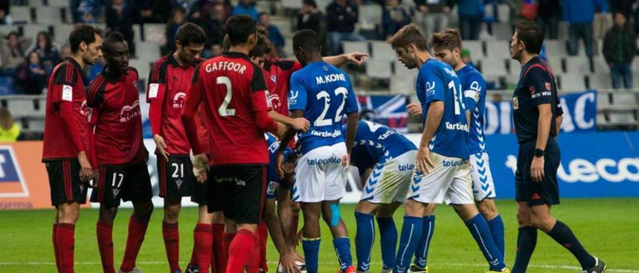 El árbitro, Figueroa Vázquez, observa a jugadores del Oviedo y el Mirandés antes de lanzarse una falta.