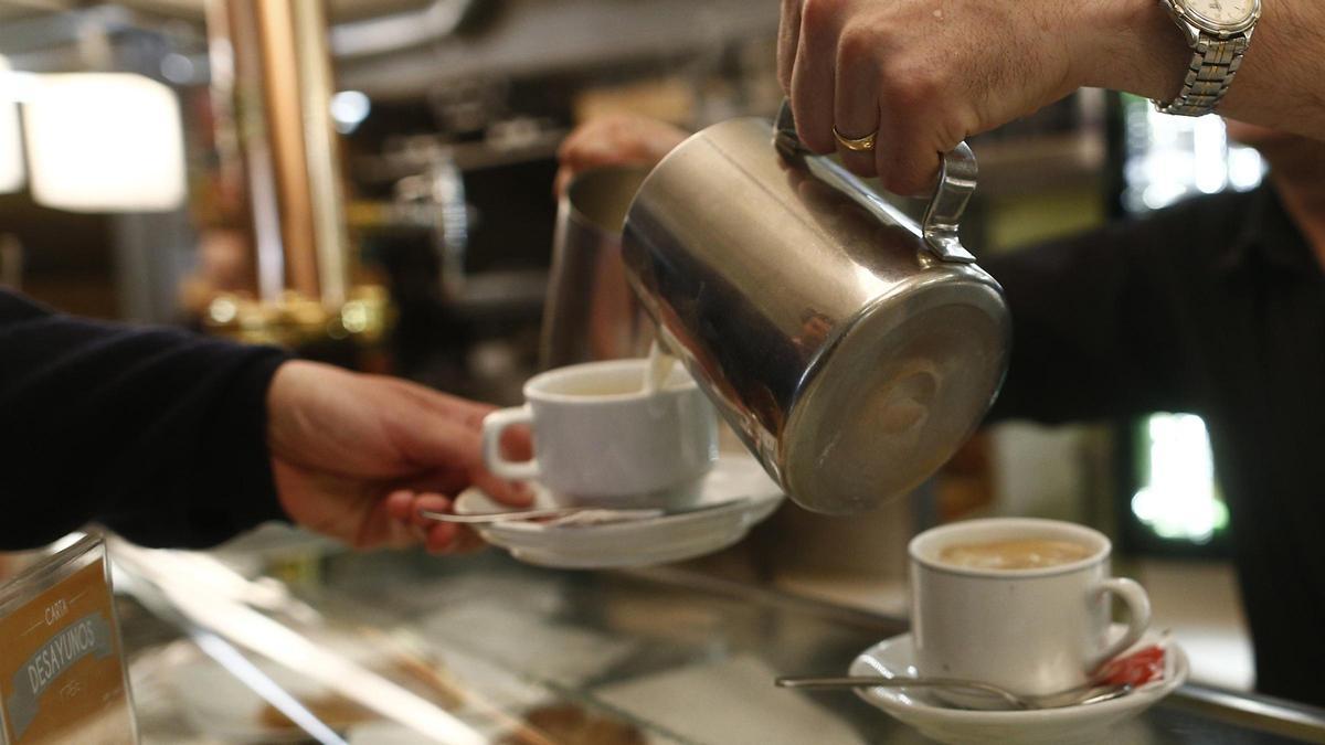 Un camarero sirve café en una cafetería.