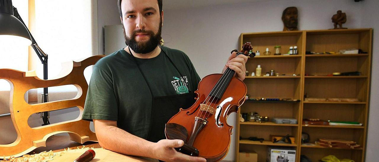 Martín González sosteniendo uno de sus violines en su taller de Vilaboa.   | // GUSTAVO SANTOS
