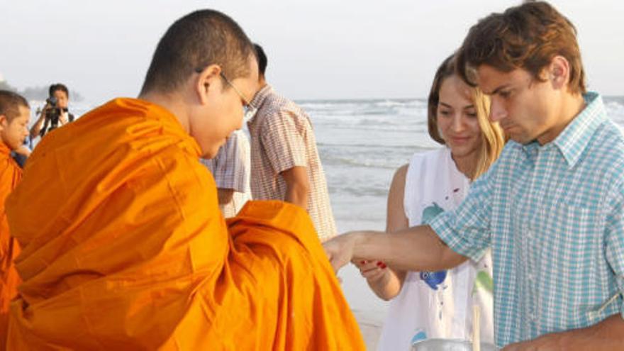 David Ferrer (dcha) y su novia Marta Tornel (2  dcha) dan una limosna a un monje budista en la ciudad turística de Hua Hin (Tailandia) en enero de 2015