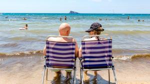 Una pareja sentada en la orilla del mar en Benidorm.