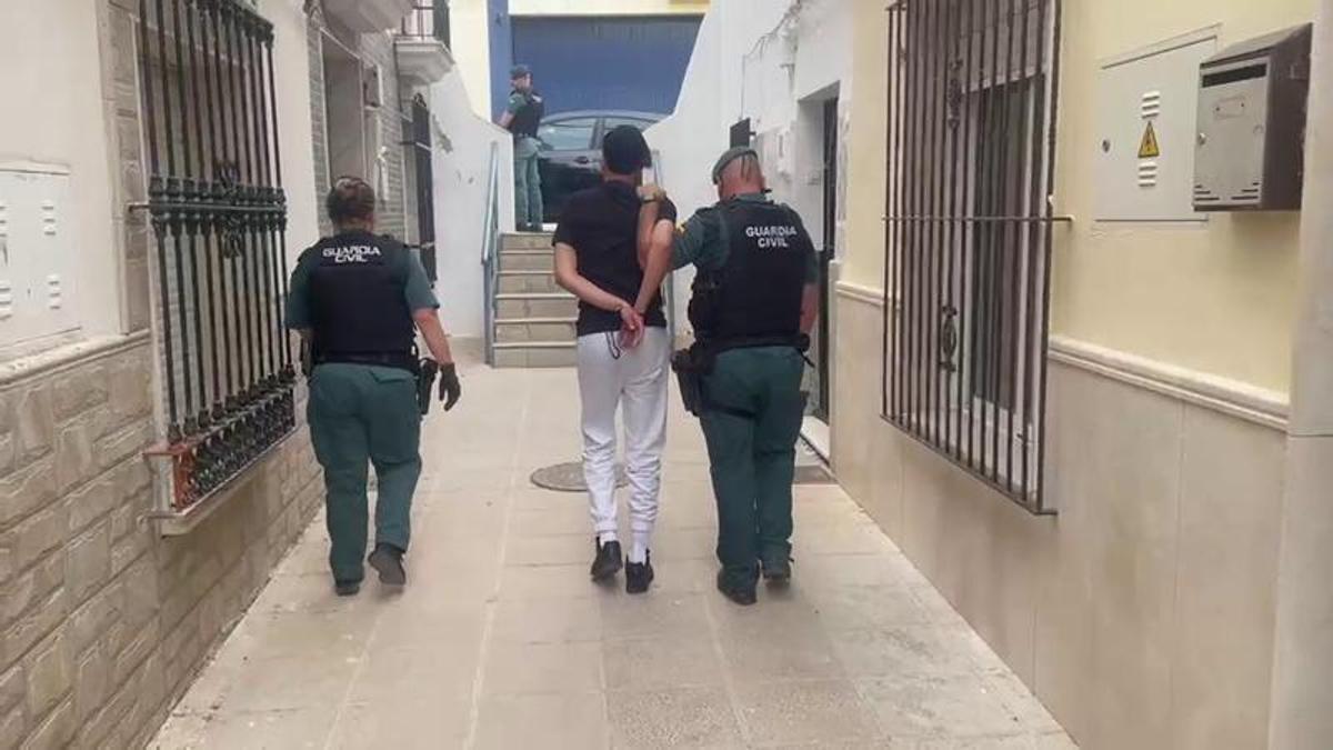 Agentes de la Guardia Civil se llevan a uno de los cuatro detenidos tras desmantelar un punto de venta de drogas en Puente Genil.