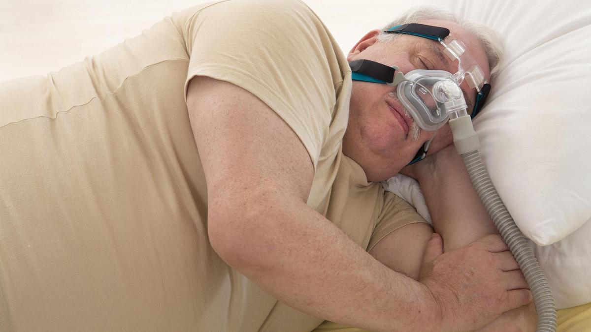 Un hombre con apnea del sueño y la máquina de CPAP.