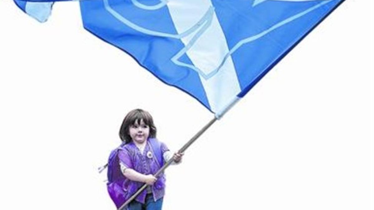 Una niña hace ondear una bandera de Escocia.