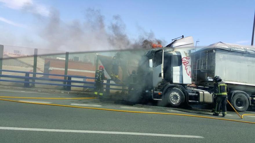 Los bomberos intentando apagar el fuego de la cabina del camión