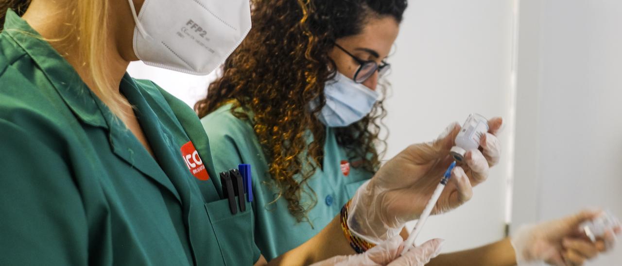 Dos médicos internas residentes preparando vacunas para administrarlas a pacientes.