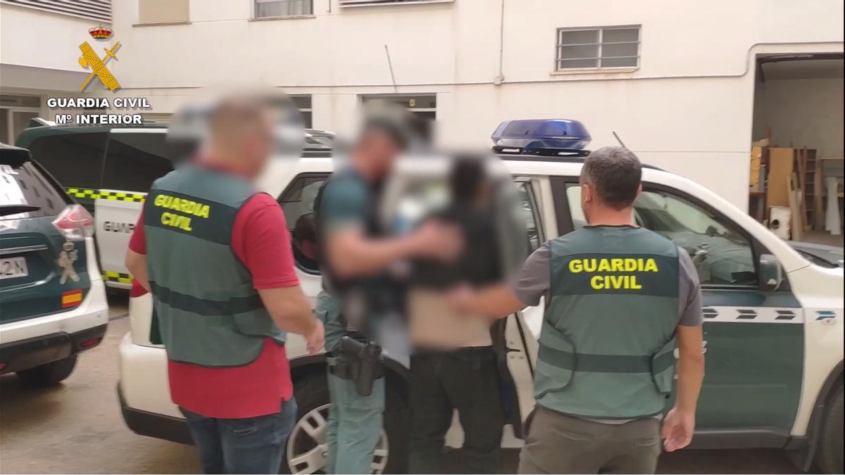 Uno de los arrestados es introducido en el vehículo de la Guardia Civil