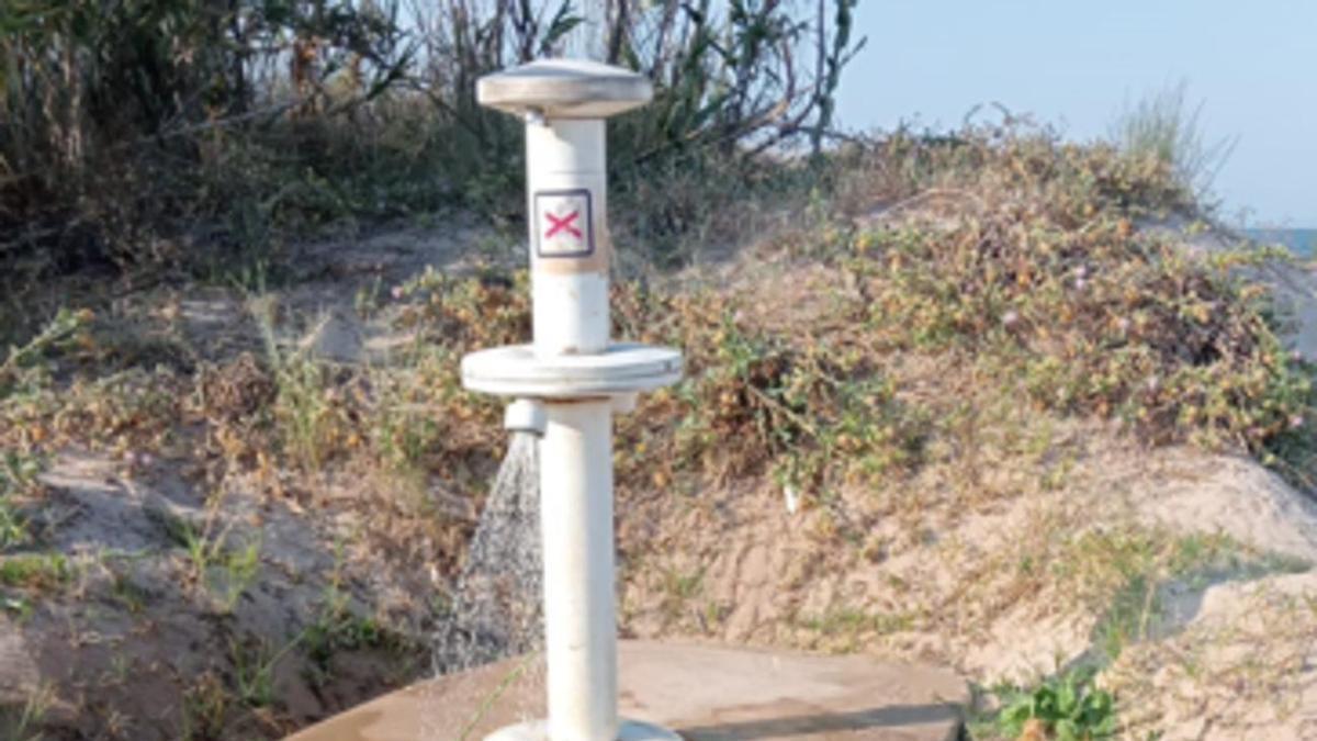Un lavapiés en marcha sin usuarios que lo utilicen, en la playa de Daimús