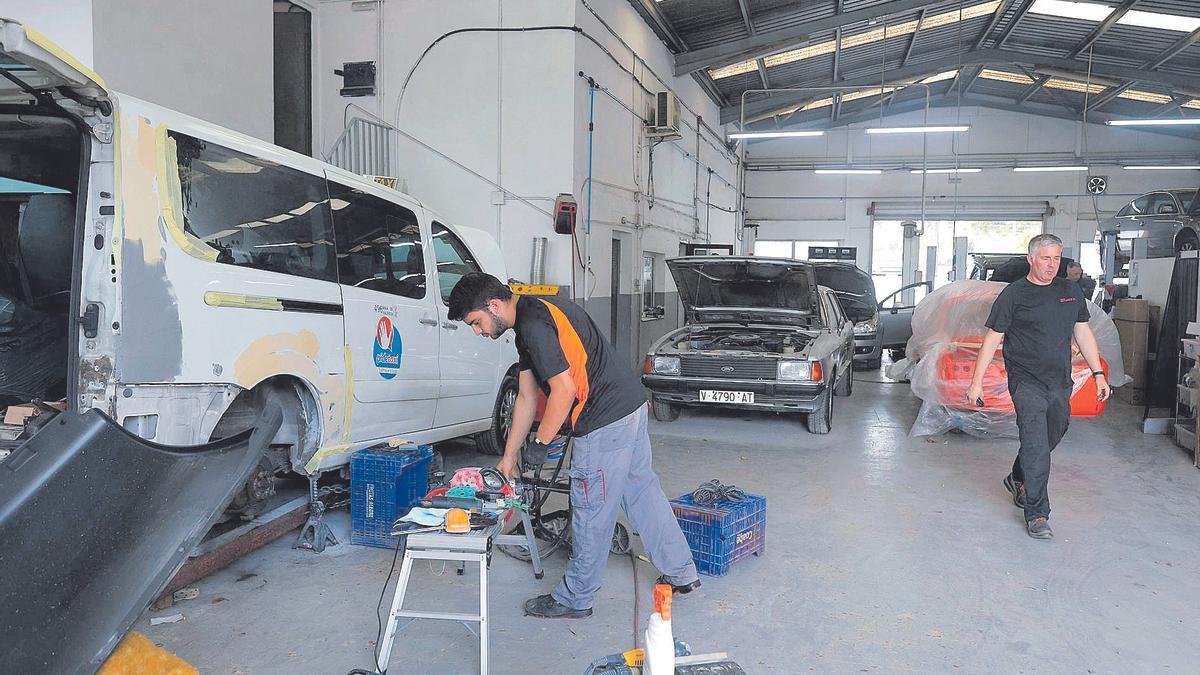 Empleados de Talleres Autocolor trabajando con las instalaciones llenas de vehículos en Bétera.