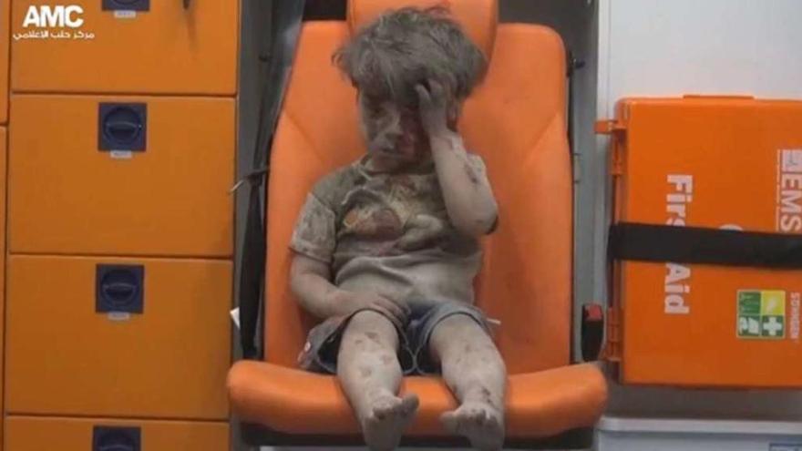 Omran, el rostro de la tragedia | Cubierto de polvo y sangre, el niño sirio, de 5 años, aguarda en una ambulancia tras ser rescatado ayer entre los escombros de una vivienda bombardeada en  Alepo. La imagen procede de un vídeo grabado por los sanitarios que le recogieron.