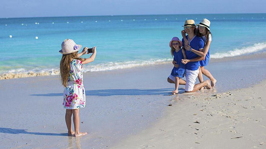 Una niña fotografía a su familia con un móvil.