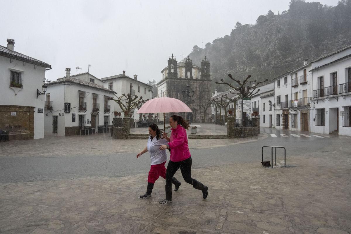 Dos vecinas de Grazalema corren por una calle inundada debido a las intensas lluvias que se registran este miércoles en la localidad gaditana, y que suceden al mes de enero más lluvioso desde principios del siglo XX lo que ha hecho que se acumule gran cantidad de agua en el subsuelo. EFE/Román Ríos