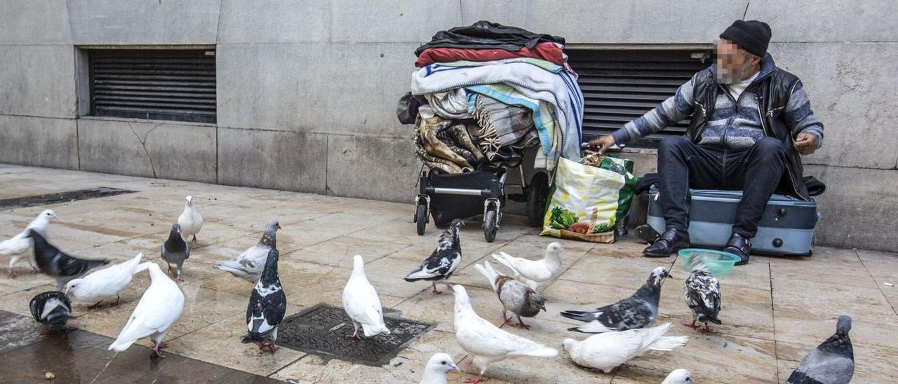 Un hombre pide dinero en una calle de Alicante, junto a sus pertenencias.  | ALEX DOMÍNGUEZ