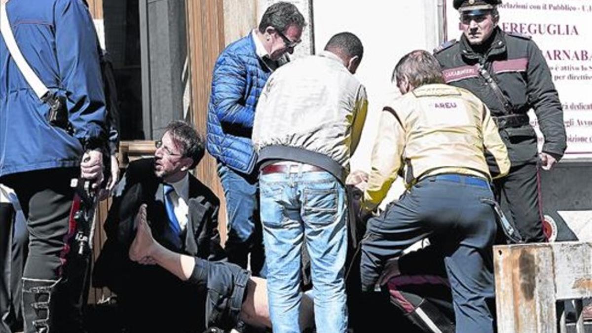 Uno de los heridos en el tiroteo de Milán recibe atención frente al edificio del juzgado, ayer.
