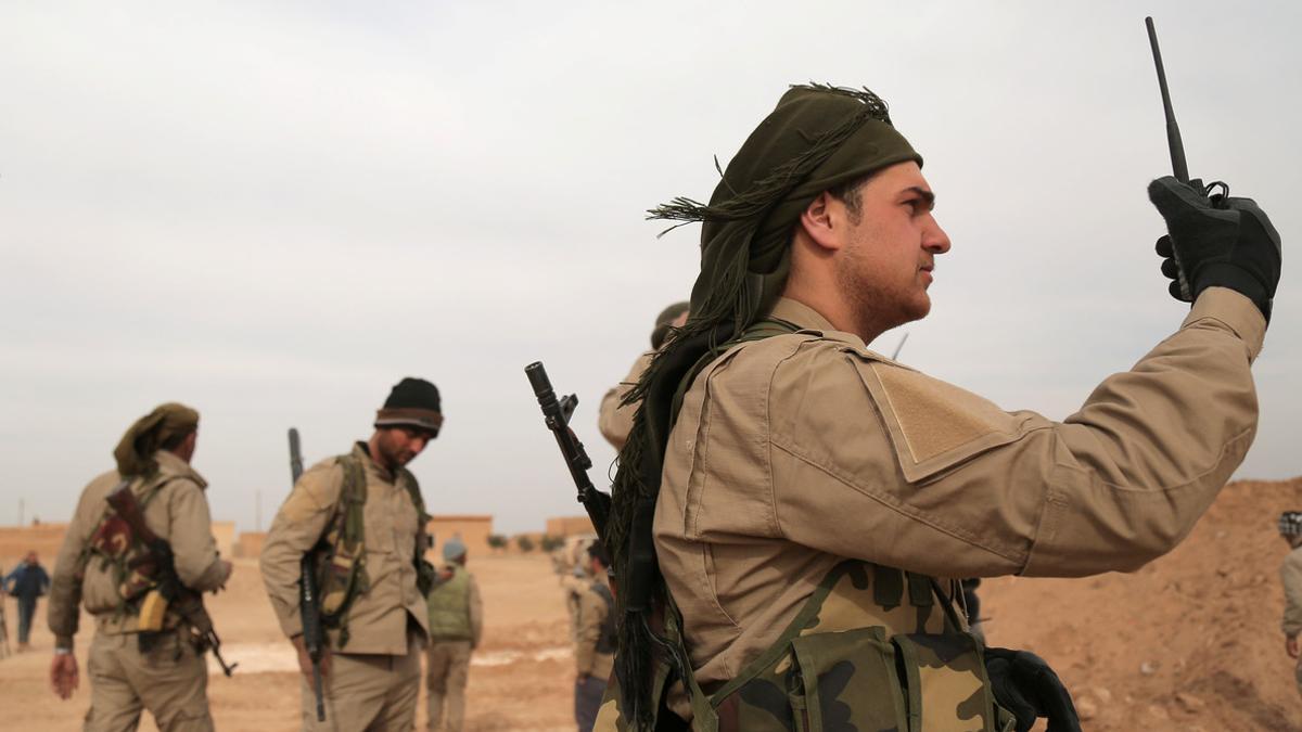 A Syrian Democratic Forces (SDF) fighter carries a walkie talkie as he stands with his fellow fighters during an offensive against Islamic State militants in northern Raqqa province