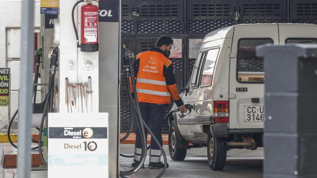 Un trabajador de una estación de servicio del centro de Cáceres echa gasolina en un vehículo.