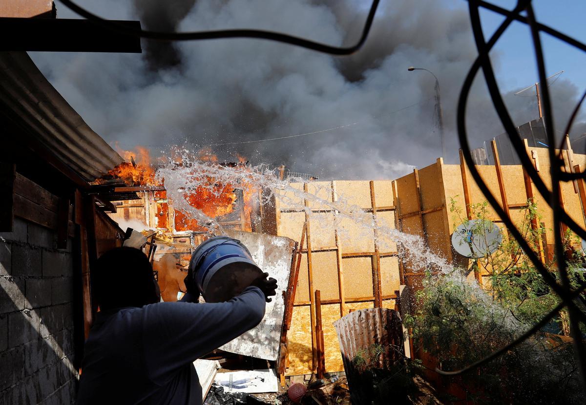 Un hombre arroja agua para ayudar a extinguir el incendio en el barrio Laguna Verde.