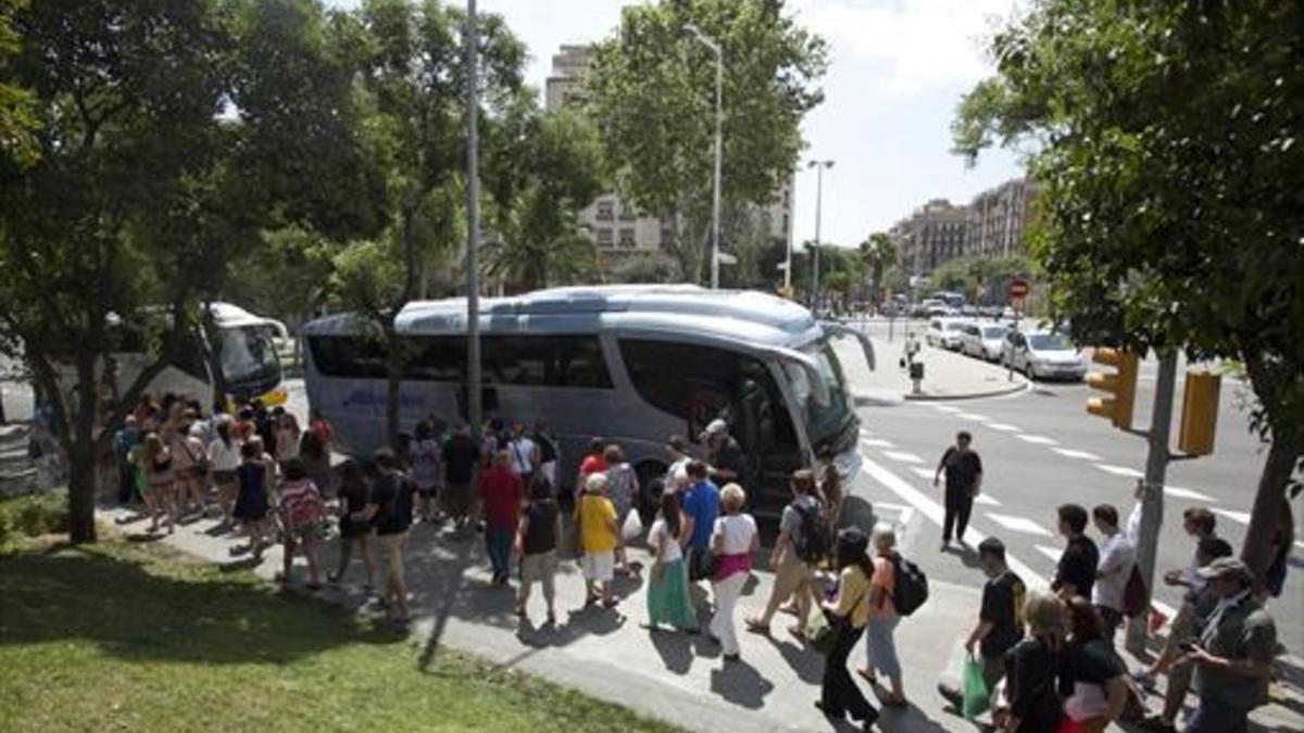 Grupos de turistas excursionistas, que visitan Barcelona sin pernoctar, se dirigen a los autocares aparcados en la zona de Diagonal-Aragó después de ver el templo de la Sagrada Família.