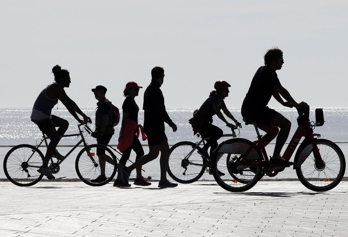 Peatones y ciclistas en un paseo marítimo.