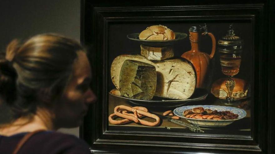 A la derecha, una mujer observa la obra &quot;Bodegón con quesos, almendras y pretzels&quot;, de Clara Peeters. A la izquierda, la obra &quot;Bodegón con flores, copas doradas, monedas y conchas&quot;.