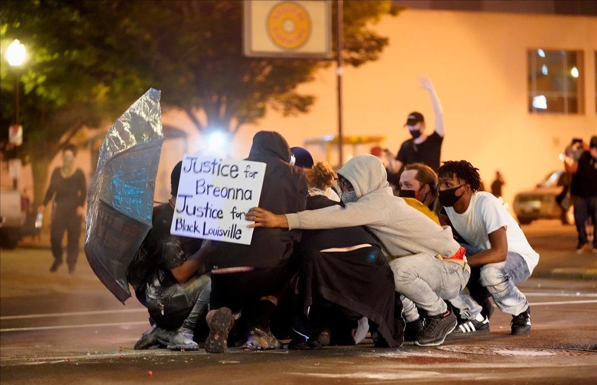 Manifestantes en el suelo intentar repeler el ataque congas pimienta en Louisville, Kentucky.