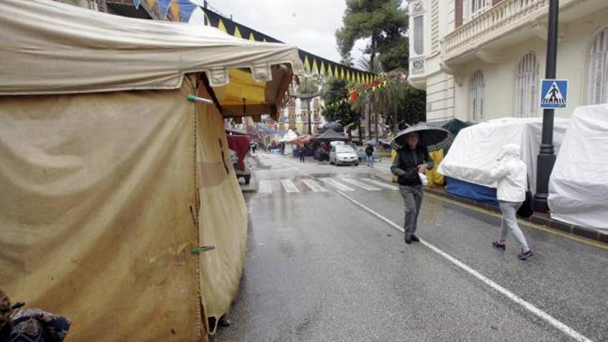 Varias personas caminan, ayer, entre algunos puestos del Mercado Medieval cerrados por la lluvia .