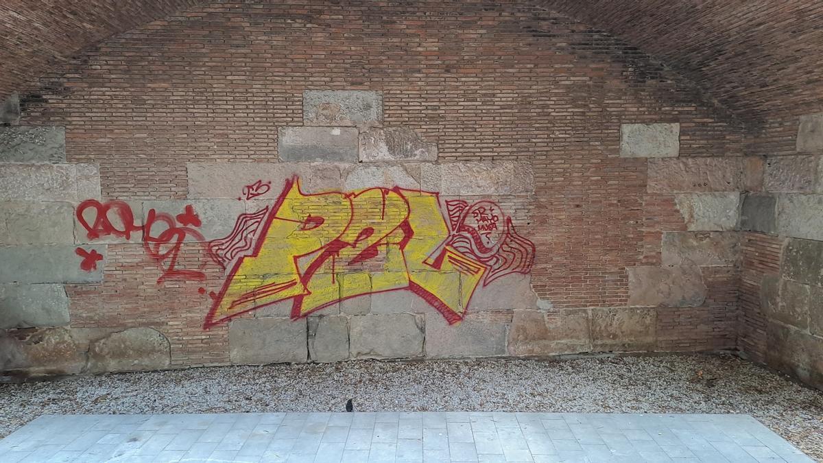 Un 'tag' de grafiti pintado sobre la muralla romana de Barcelona