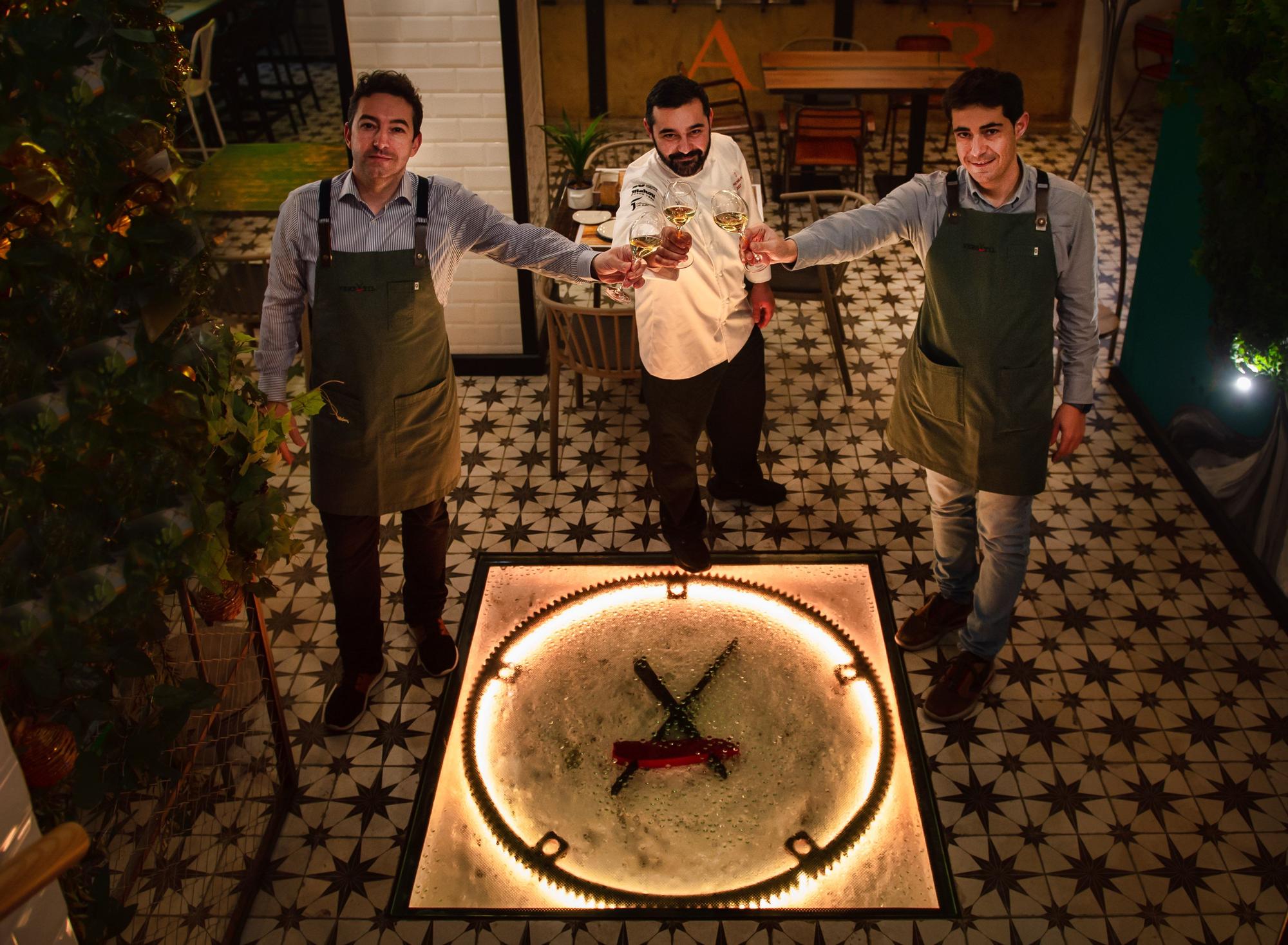 David, Alejandro y José Luis brindan ante el logo del restaurante.