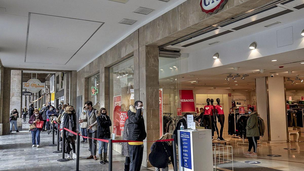 Imagen de colas frente a los grandes comercios horas antes de que se aplicara el cierre ordenado por el Govern. | B. RAMON