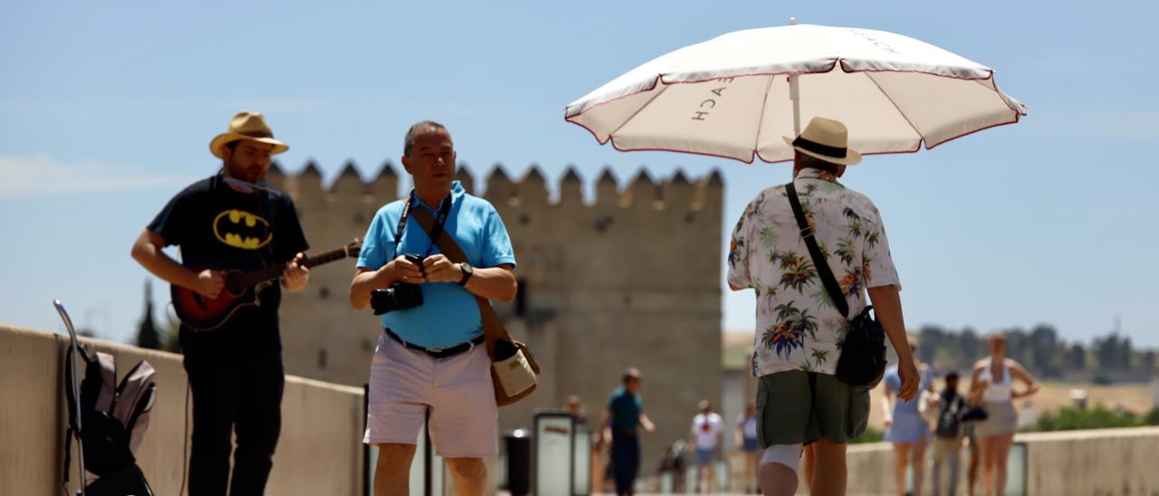 Un grupo de turistas pasea por el Puente Romano de Córdoba en una jornada de intenso calor.