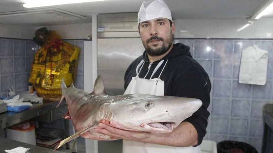 Abel Simes con el pequeño tiburón en su pescadería. // Santos Álvarez