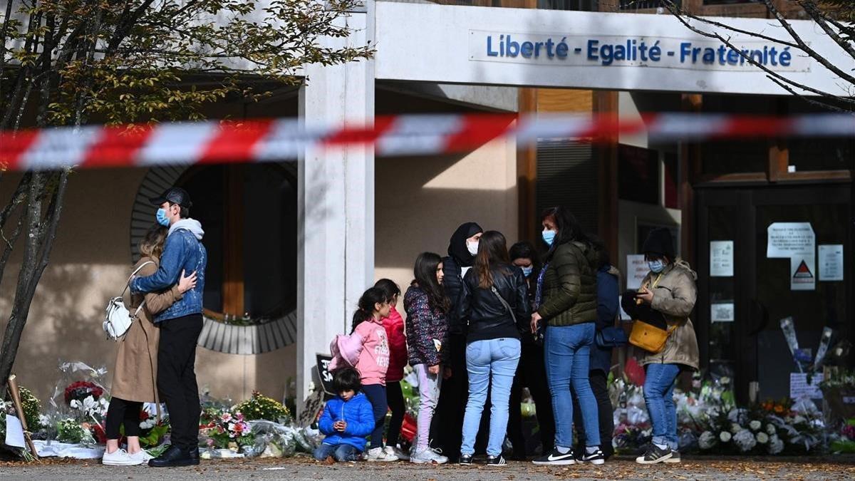 La gente coloca flores en los alrededores del centro de secundaria Bois d'Aulne en homenaje al maestro de historia asesinado Samuel Paty.