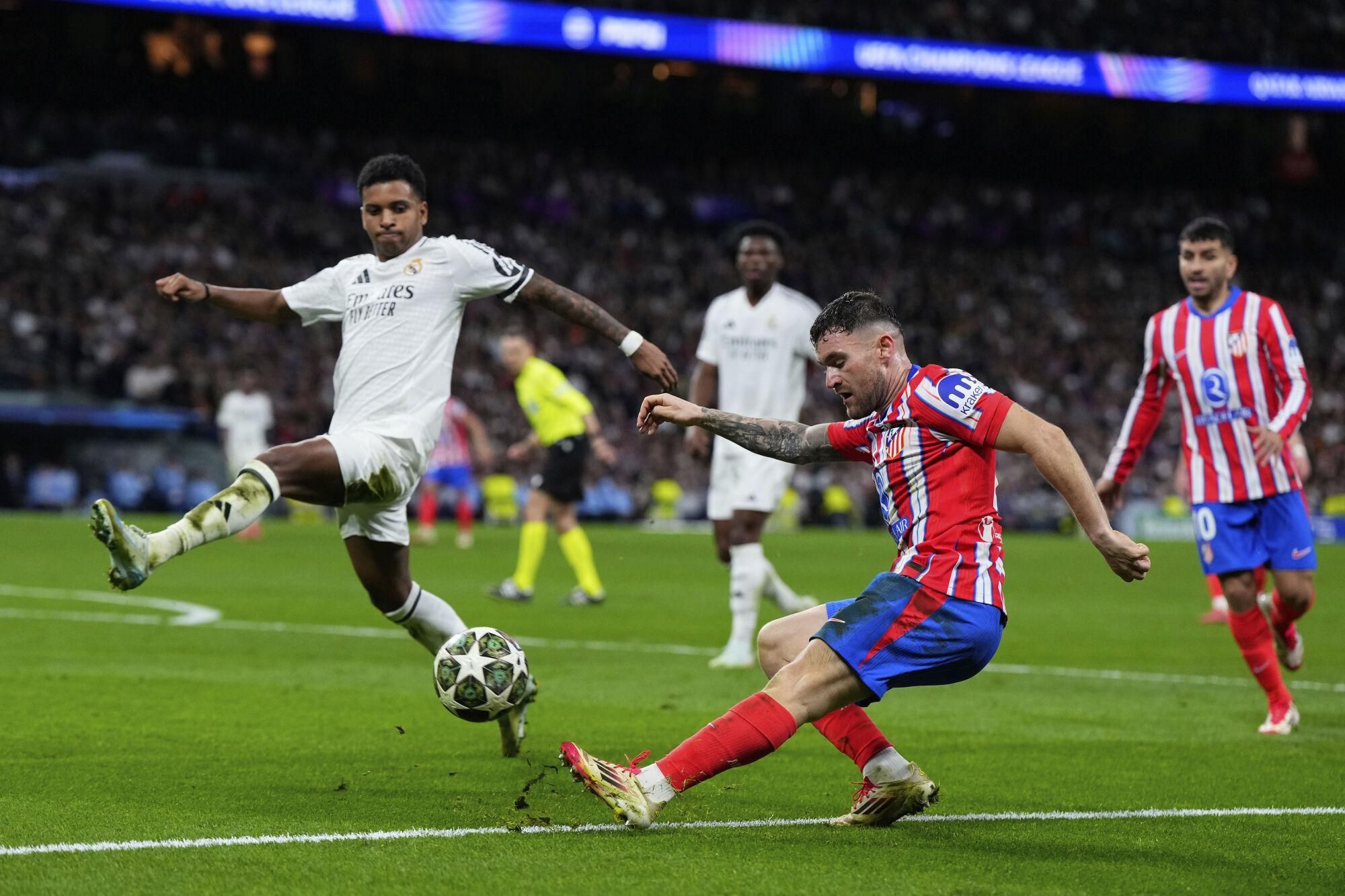 Atletico Madrid's Javi Galan, center, passes the ball past Real Madrid's Rodrygo during the Champions League round of 16 first leg soccer match between Real Madrid and Atletico Madrid at the Bernebeu stadium in Madrid, Spain, Tuesday, March 4, 2025. (AP Photo/Manu Fernandez)